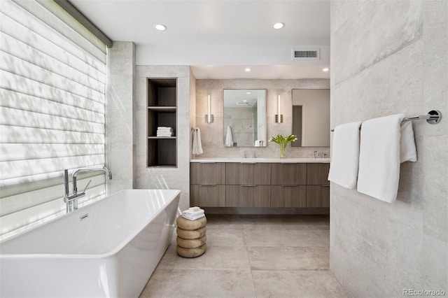 bathroom with visible vents, double vanity, recessed lighting, a soaking tub, and a sink