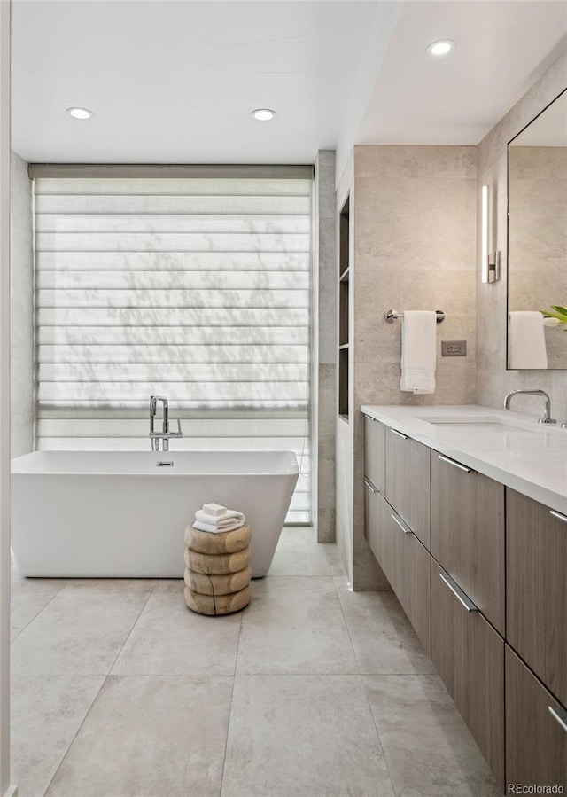 bathroom featuring a freestanding tub, a wealth of natural light, tile patterned flooring, and vanity