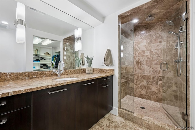 full bath featuring vanity, visible vents, a walk in closet, and a stall shower