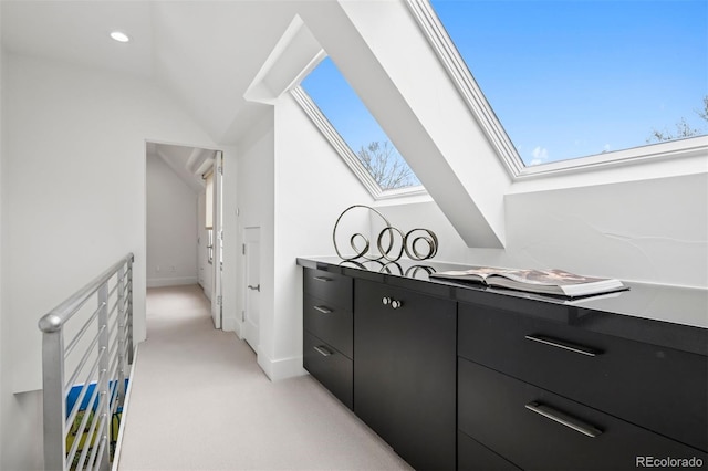 interior space featuring vaulted ceiling with skylight, baseboards, light carpet, and recessed lighting
