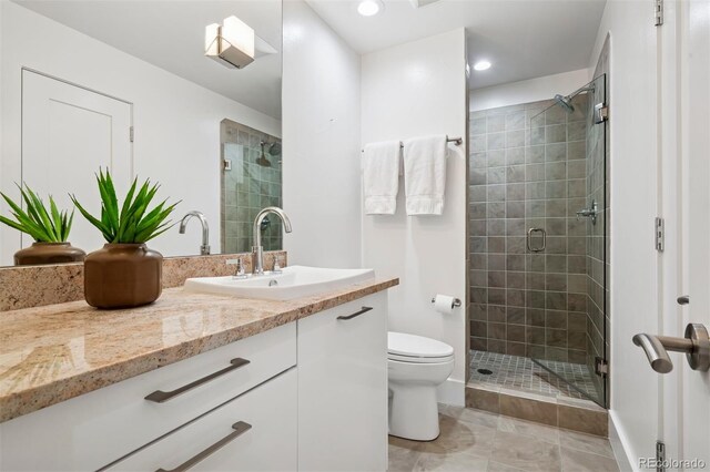full bathroom featuring vanity, baseboards, a stall shower, and toilet