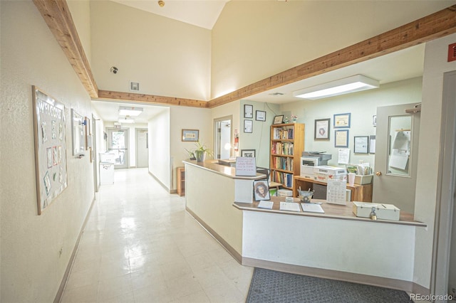 corridor with a towering ceiling, beam ceiling, and light tile patterned floors