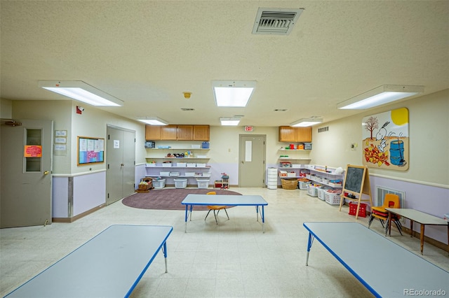 rec room featuring a textured ceiling and light tile patterned floors