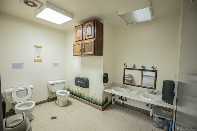 bathroom featuring dual sinks, toilet, and tile patterned flooring