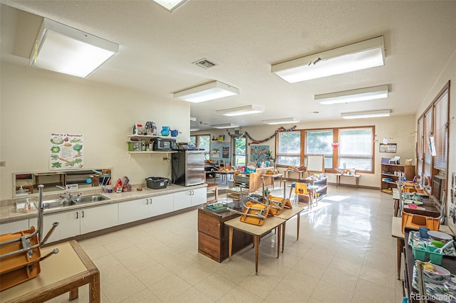 interior space with light tile patterned flooring, sink, and a textured ceiling