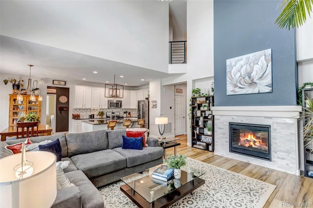 21658 E Tallkid Ave, Parker, CO 80138 - living area featuring light wood-style floors, a fireplace, a high ceiling, a chandelier, and recessed lighting