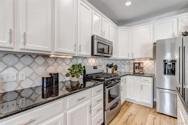 21658 E Tallkid Ave, Parker, CO 80138 - kitchen with appliances with stainless steel finishes, white cabinetry, dark stone counters, and decorative backsplash