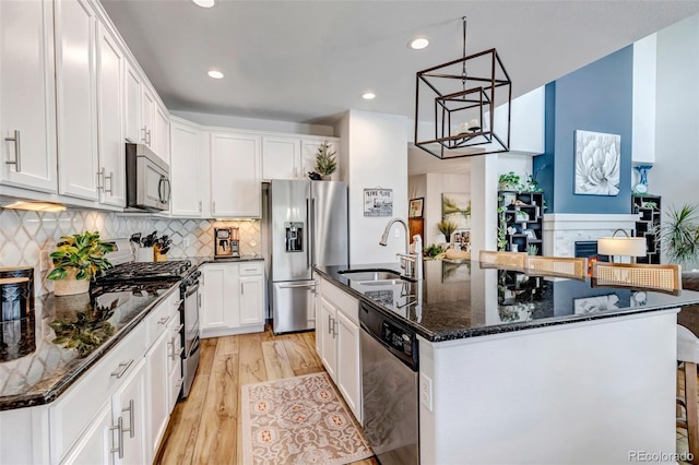 21658 E Tallkid Ave, Parker, CO 80138 - kitchen featuring stainless steel appliances, light wood finished floors, white cabinets, an island with sink, and recessed lighting