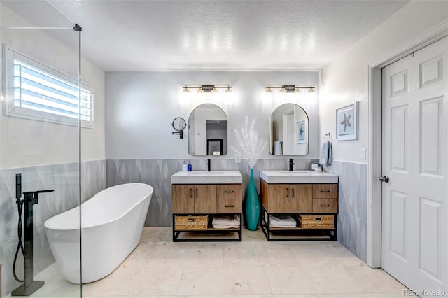 21658 E Tallkid Ave, Parker, CO 80138 - full bath featuring tile walls, a freestanding tub, two vanities, a wainscoted wall, and a textured ceiling