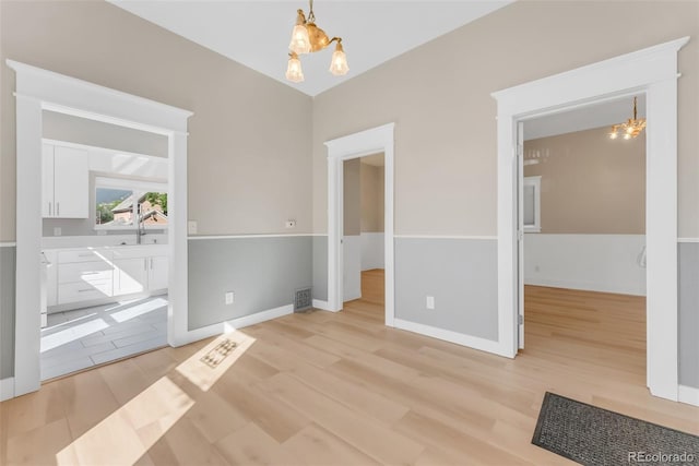 2323 W Pikes Peak Ave, Colorado Springs, CO 80904 - unfurnished bedroom featuring a chandelier, light wood-style floors, and connected bathroom