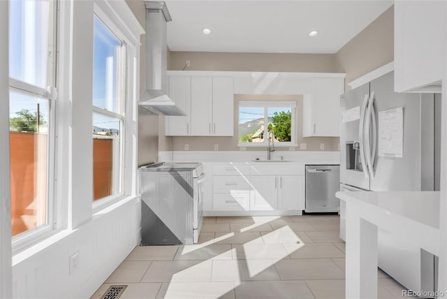 2323 W Pikes Peak Ave, Colorado Springs, CO 80904 - kitchen featuring stainless steel dishwasher, stove, wall chimney exhaust hood, light tile patterned floors, and white cabinets