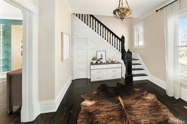 staircase with ornamental molding, wood-type flooring, visible vents, and baseboards