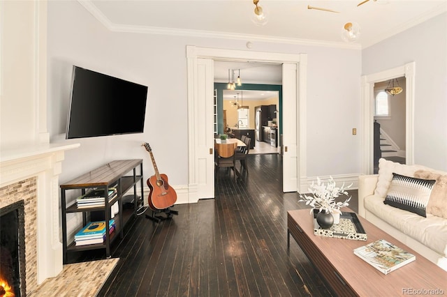 living room featuring a warm lit fireplace, baseboards, stairs, ornamental molding, and hardwood / wood-style floors