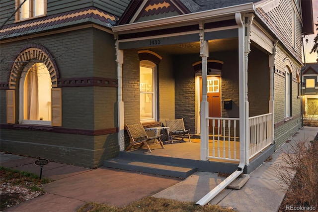 view of exterior entry with covered porch and brick siding