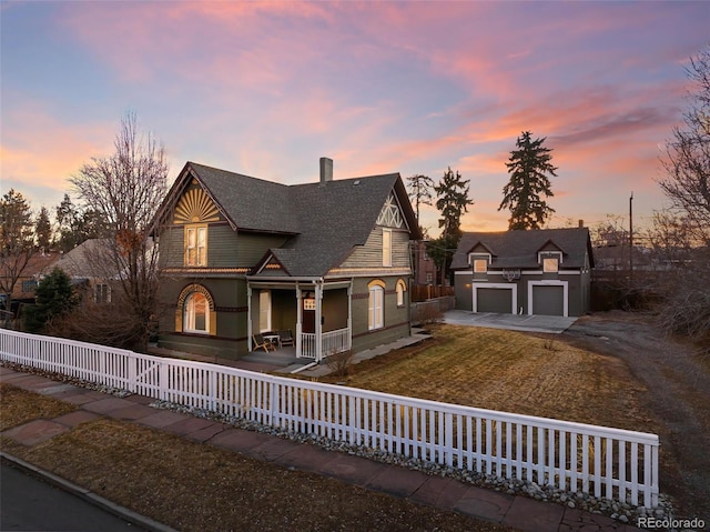 victorian home with a garage, a fenced front yard, a chimney, an outdoor structure, and a porch