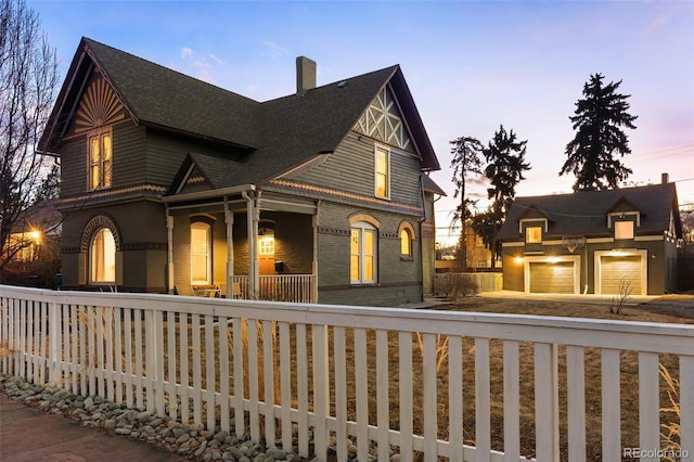 view of front of home with a shingled roof, a chimney, fence, a porch, and brick siding