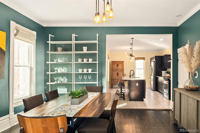 dining room with a notable chandelier, light wood-style floors, and crown molding