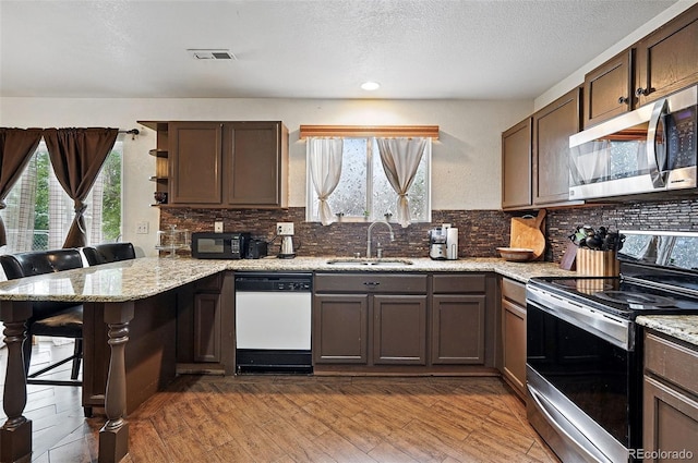 1419 Swan Ave, Brighton, CO 80601 - kitchen with appliances with stainless steel finishes, a sink, a peninsula, tasteful backsplash, and a textured ceiling