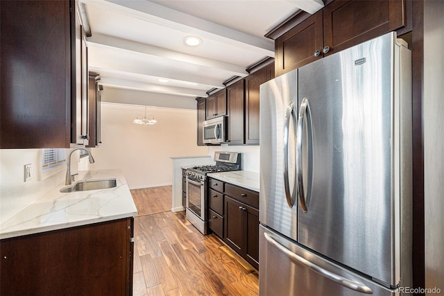 kitchen with light stone countertops, hardwood / wood-style floors, beam ceiling, stainless steel appliances, and sink