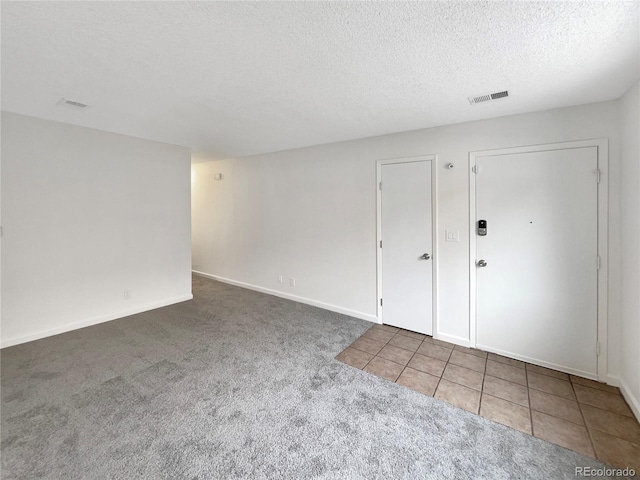 carpeted empty room featuring a textured ceiling