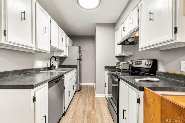 16259 W 10th Ave Unit L2, Golden, CO 80401 - kitchen with appliances with stainless steel finishes, under cabinet range hood, dark countertops, white cabinetry, and light wood-style flooring