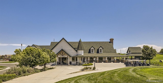 view of front of house featuring covered porch, a front yard, and a chimney