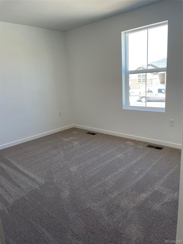 spare room featuring baseboards and dark carpet