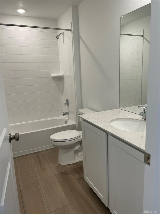 full bathroom featuring wood finished floors, toilet, vanity, and tub / shower combination