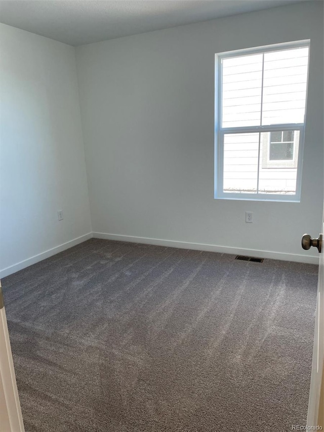 unfurnished room with dark colored carpet and baseboards
