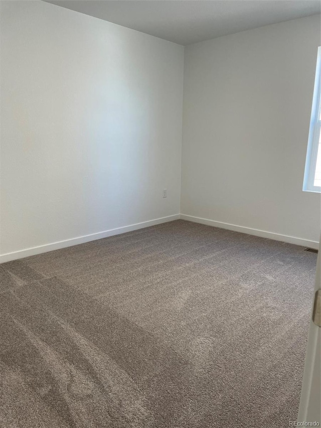 carpeted spare room with baseboards