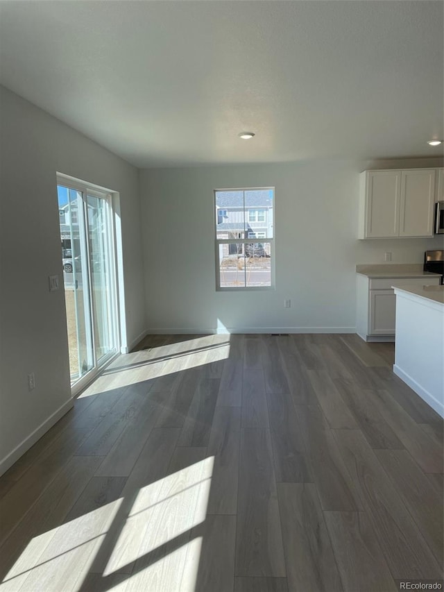 unfurnished dining area with plenty of natural light, recessed lighting, baseboards, and dark wood finished floors