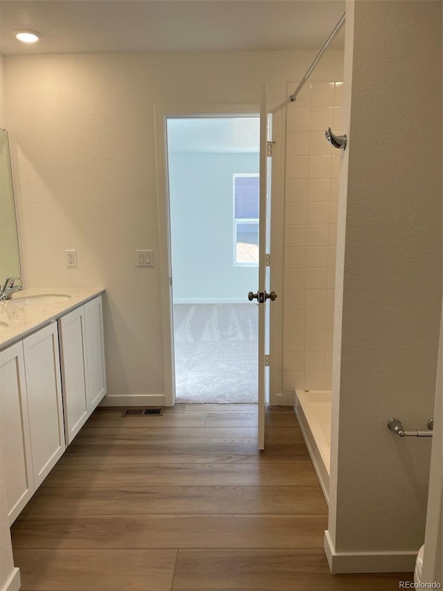 full bath featuring a shower, wood finished floors, vanity, and baseboards