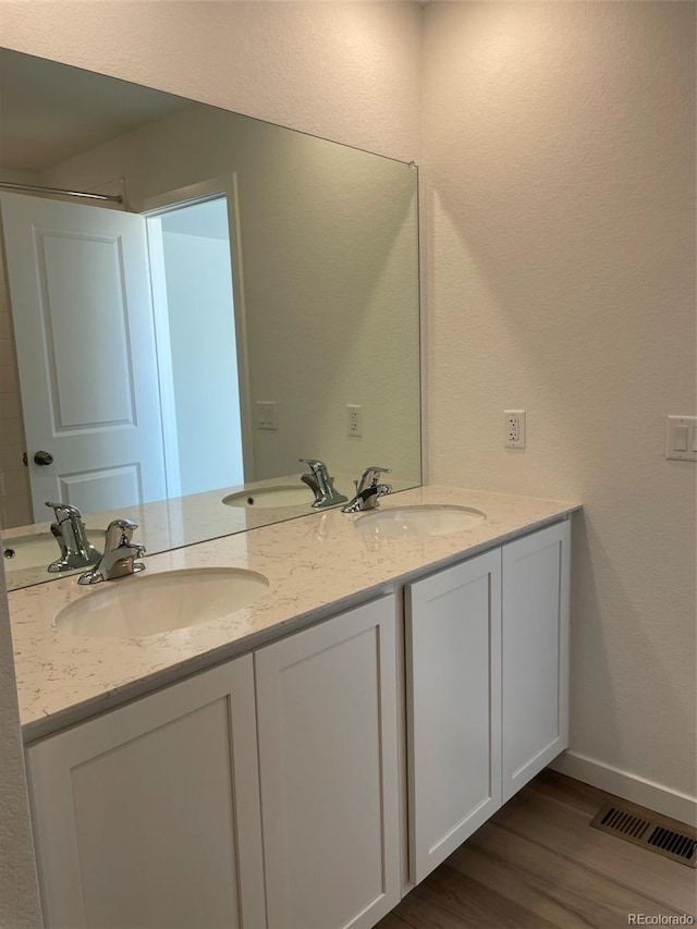 full bathroom with wood finished floors, double vanity, and baseboards