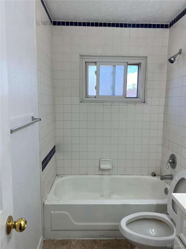 full bathroom featuring tile flooring, vanity, tiled shower / bath combo, and toilet