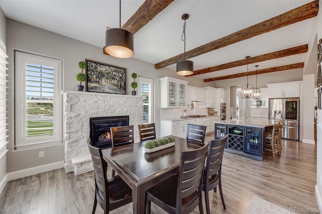360 Basilwood Way, Highlands Ranch, CO 80126 - dining room featuring a stone fireplace, light wood finished floors, beamed ceiling, and a chandelier