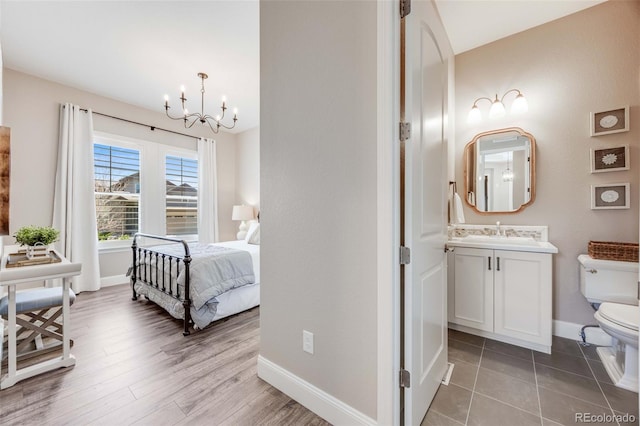 360 Basilwood Way, Highlands Ranch, CO 80126 - bedroom featuring a chandelier, light wood finished floors, and ensuite bathroom