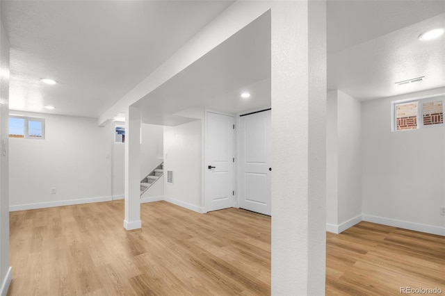 basement with light hardwood / wood-style flooring and a textured ceiling