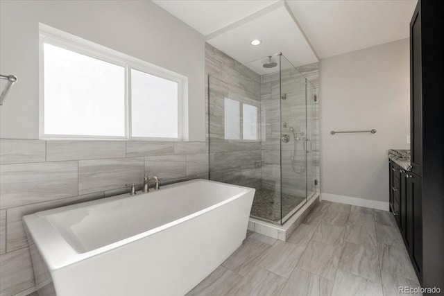 bathroom with vanity, independent shower and bath, and tile walls