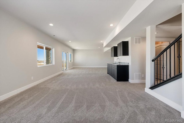 unfurnished living room featuring light carpet and indoor wet bar