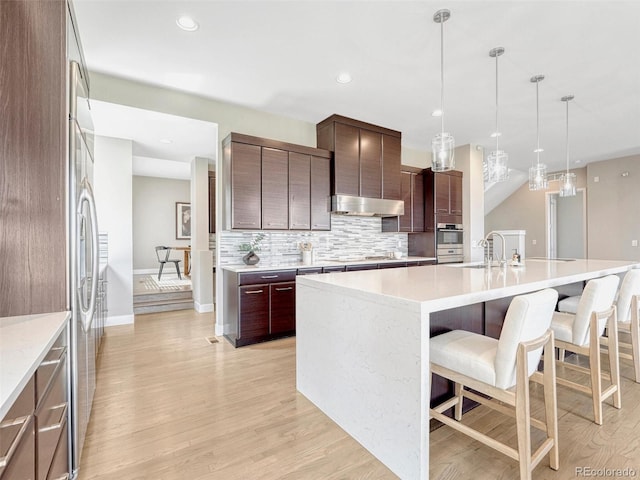 9395 Night Star Pl, Lone Tree, CO 80124 - kitchen with a breakfast bar, light wood-style floors, tasteful backsplash, light countertops, and recessed lighting
