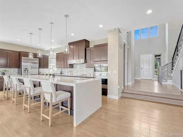 9395 Night Star Pl, Lone Tree, CO 80124 - kitchen featuring stainless steel appliances, light countertops, tasteful backsplash, light wood-type flooring, and recessed lighting