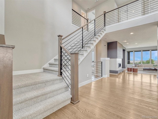 9395 Night Star Pl, Lone Tree, CO 80124 - stairs featuring wood finished floors, a fireplace with raised hearth, a towering ceiling, and recessed lighting