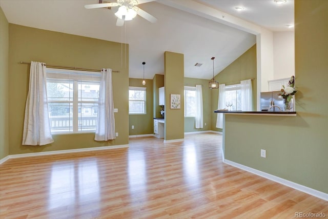 unfurnished living room featuring a wealth of natural light, vaulted ceiling, and light wood-style flooring