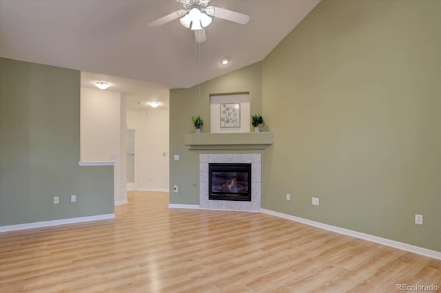 unfurnished living room with lofted ceiling, a fireplace, baseboards, and light wood-style floors