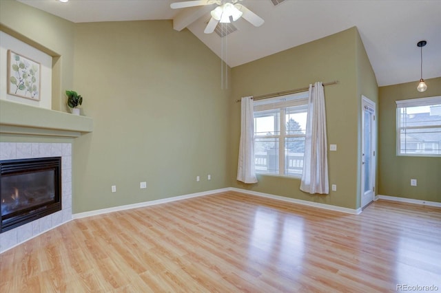 unfurnished living room with baseboards, a tile fireplace, wood finished floors, and a healthy amount of sunlight