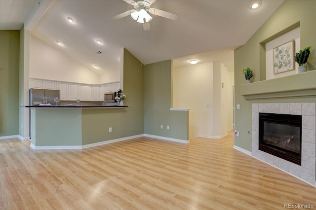 unfurnished living room featuring a ceiling fan, baseboards, a fireplace, and light wood finished floors