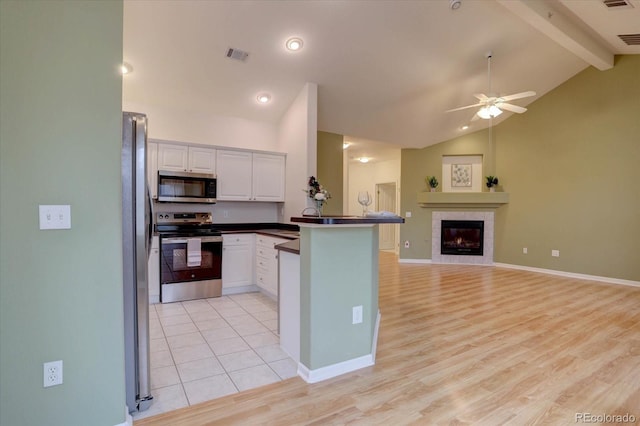 kitchen featuring visible vents, appliances with stainless steel finishes, open floor plan, a peninsula, and a fireplace