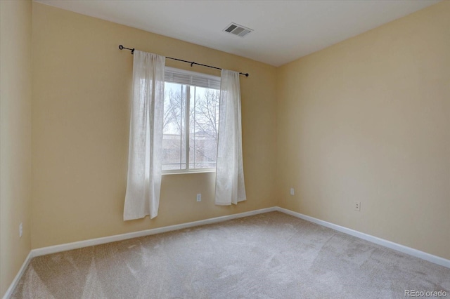 carpeted spare room with visible vents and baseboards