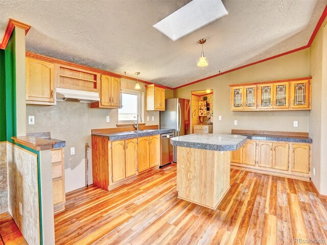 kitchen with a kitchen island, dishwasher, lofted ceiling with skylight, under cabinet range hood, and light wood-style flooring