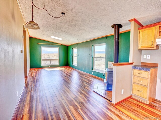 unfurnished living room featuring baseboards, a wood stove, lofted ceiling, and wood finished floors